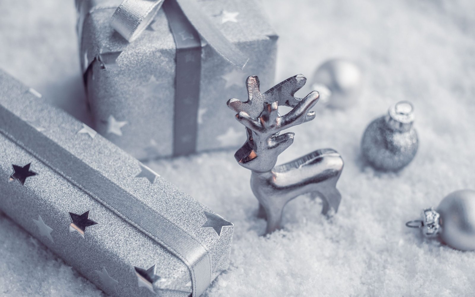 Silvery holiday gifts and reindeer on snow, perfect Christmas decor.